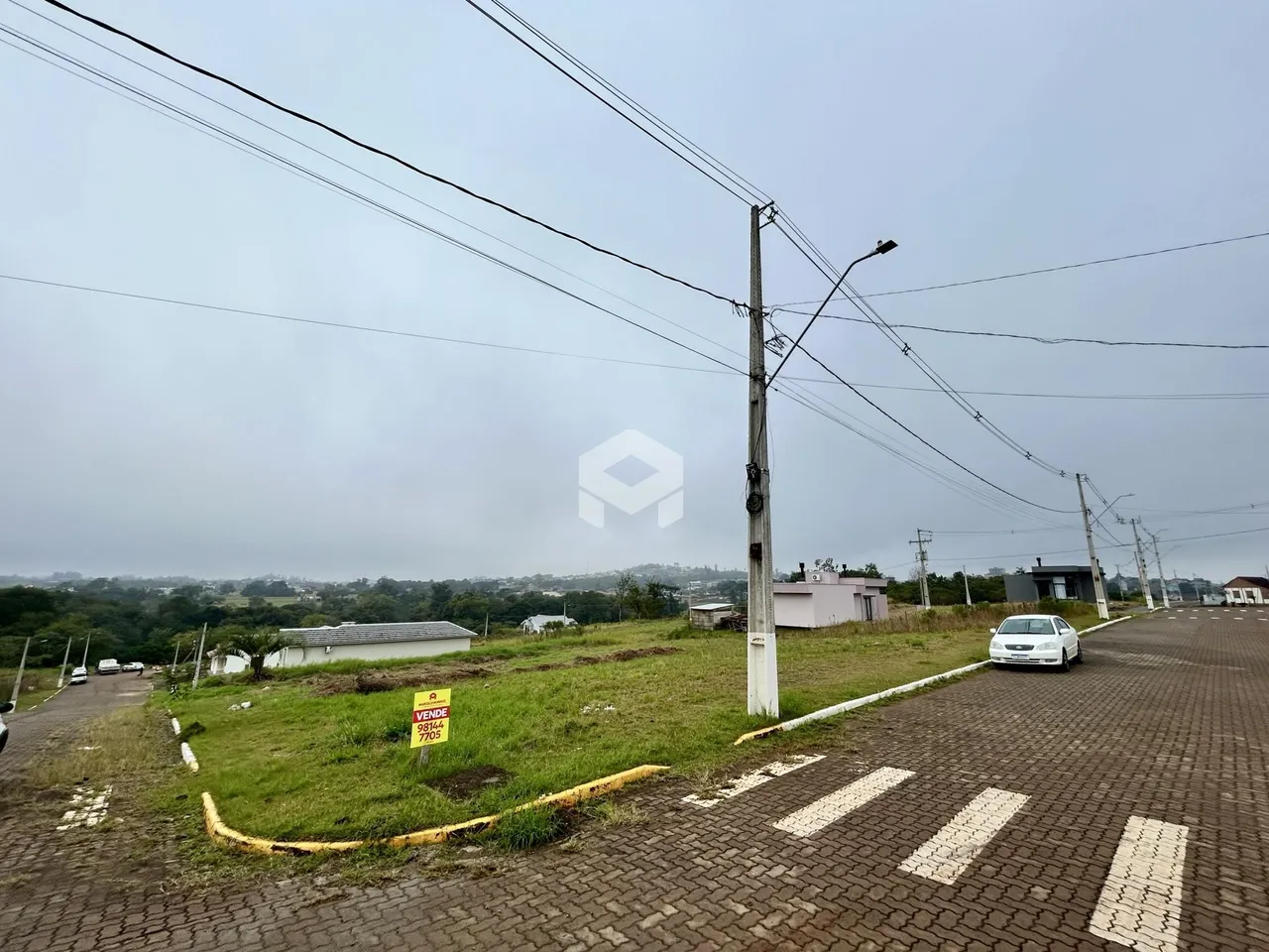 Vista da rua com gramado e postes de energia em Lajeado, Brasil.