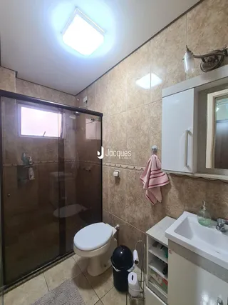 Foto interna de um banheiro com piso cerâmico e box de vidro.