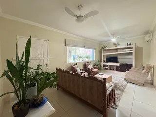 Sala de estar com sofá de madeira e plantas em um apartamento no Brasil.
