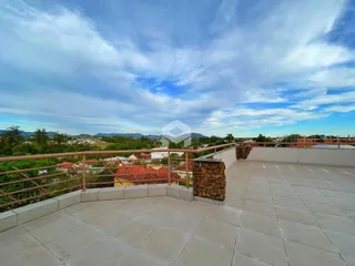 Vista de uma varanda com piso de cerâmica e parede de pedra.