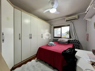 Quarto com armários embutidos e cama de cor vermelha.