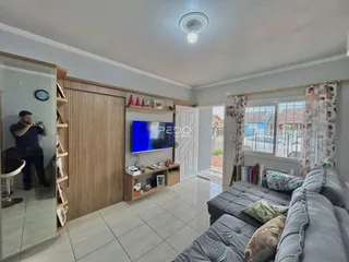 Sala de estar com sofá e televisão em ambiente interno.