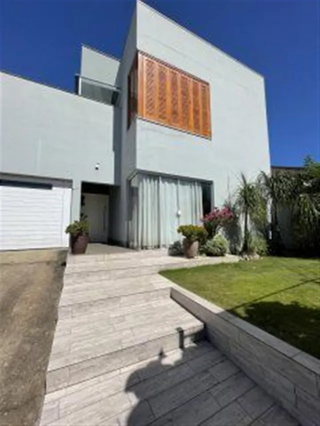 Fachada moderna de uma residência com jardim e calçada de pedras.