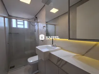 Banheiro moderno com box de vidro e bancada clara.