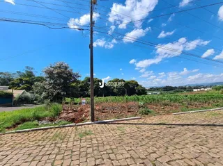 Vista externa de uma propriedade com paisagismo e pavimento de tijolos.