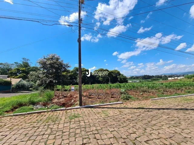 Vista externa de uma propriedade com paisagismo e pavimento de tijolos.