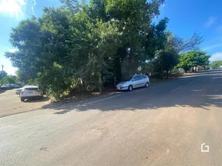Vista da rua com árvores e um carro estacionado na lateral.