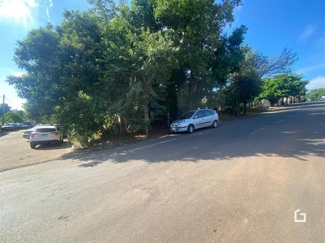 Vista da rua com árvores e um carro estacionado na lateral.