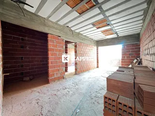 Interior de uma estrutura em construção com paredes de tijolo aparente.