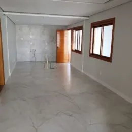 Interior de um cômodo amplo com piso claro e porta de madeira.
