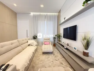 Sala de estar moderna com sofá grande e televisão montada na parede.
