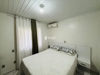 Quarto interno com cama e cortinas brancas em um imóvel.