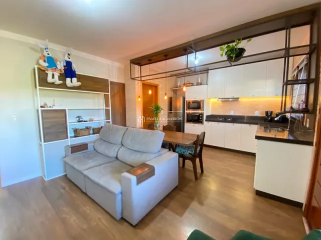 Sala de estar com sofá e móveis de madeira clara em um apartamento.