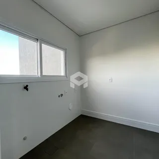 Interior de um cômodo com paredes brancas e piso escuro.