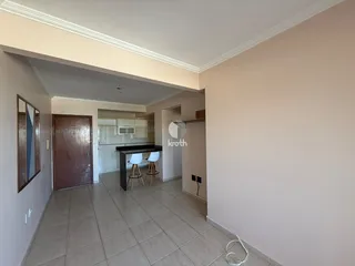 Vista interna de uma área de transição com cozinha e sala de jantar.