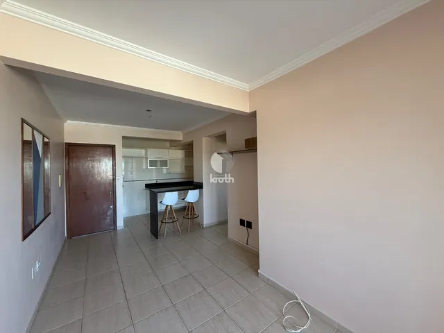 Vista interna de uma área de transição com cozinha e sala de jantar.