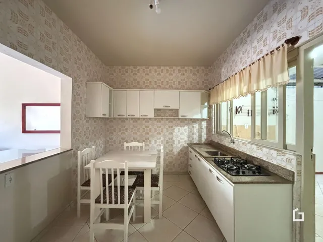 Foto da sala de jantar e cozinha com armários brancos e piso claro.