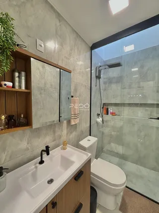 Banheiro moderno com box de vidro e revestimento em mármore cinza claro.