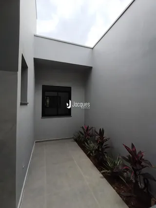 Hall de entrada moderno com piso claro e jardim ao lado.