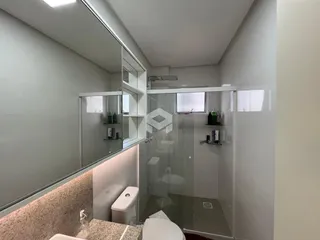 Foto de um banheiro com box de vidro e vaso sanitário.
