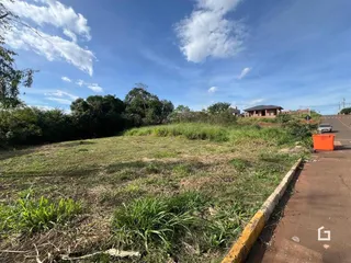 Vista da propriedade mostrando um campo gramado e um caminho de terra ao lado de uma cerca de concreto.