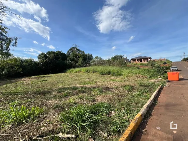 Vista da propriedade mostrando um campo gramado e um caminho de terra ao lado de uma cerca de concreto.