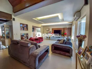 Sala de estar ampla com sofás e televisão em um ambiente claro.