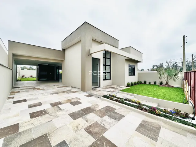 A fachada de uma casa moderna em Lajeado, Brasil, com área externa pavimentada e jardim.