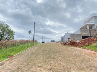 Uma estrada pavimentada se estende por uma área com vegetação ao lado de uma construção.