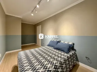 Quarto com cama e paredes em tons de bege e azul claro.