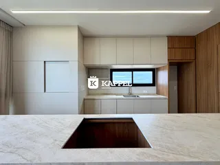 Cozinha moderna com armários claros e bancada de granito.
