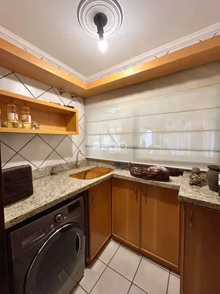 Vista da cozinha com armários de madeira e bancadas de granito.