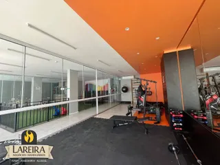 Interior de um espaço amplo com divisórias de vidro e equipamentos de ginástica.