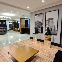 Sala de estar ampla com piso de madeira clara e iluminação clara.