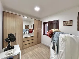 Quarto com armários em madeira e cama de casal em um imóvel no Brasil.