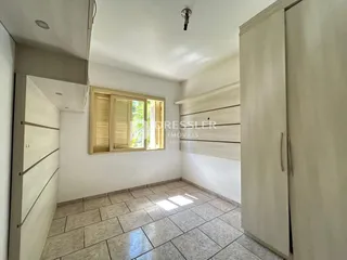 Vista interna de um corredor com piso de cerâmica e armários em uma residência.