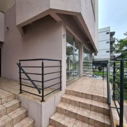 Fachada de um prédio com escadaria externa e grade de segurança.