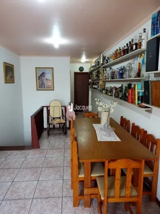 Vista interna de uma sala com mesa de jantar de madeira.