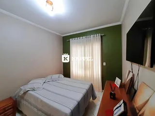 Quarto com cama e cortinas brancas em uma sala de estar.