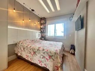 Quarto com cama e piso de madeira clara.
