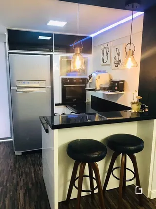 Cozinha moderna com eletrodomésticos de aço inoxidável e bancada escura.