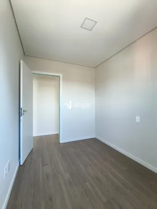 Hall de entrada com piso de madeira e paredes brancas.