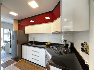 Foto de uma cozinha moderna com armários brancos e detalhes vermelhos.
