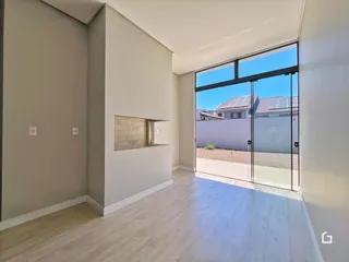 Vista interna de um ambiente com piso de madeira clara e porta de vidro que dá para o exterior.