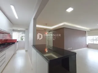 Vista de uma cozinha com armários brancos e bancadas escuras em uma residência.