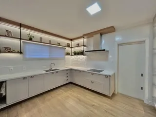 Foto de uma cozinha moderna com armários brancos e piso de madeira clara.