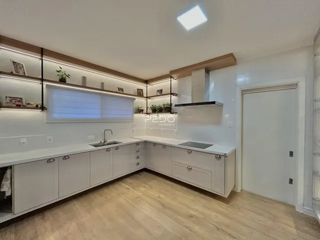 Foto de uma cozinha moderna com armários brancos e piso de madeira clara.