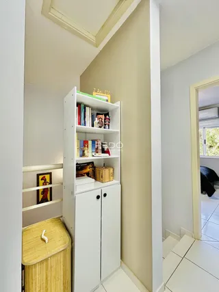 Hall de entrada com estantes brancas e móveis de armazenamento.