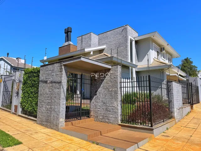 Fachada de uma casa residencial em Lajeado, Brasil, com muro de pedra e cerca de ferro.