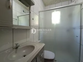 Banheiro com revestimento cerâmico e box de vidro transparente.